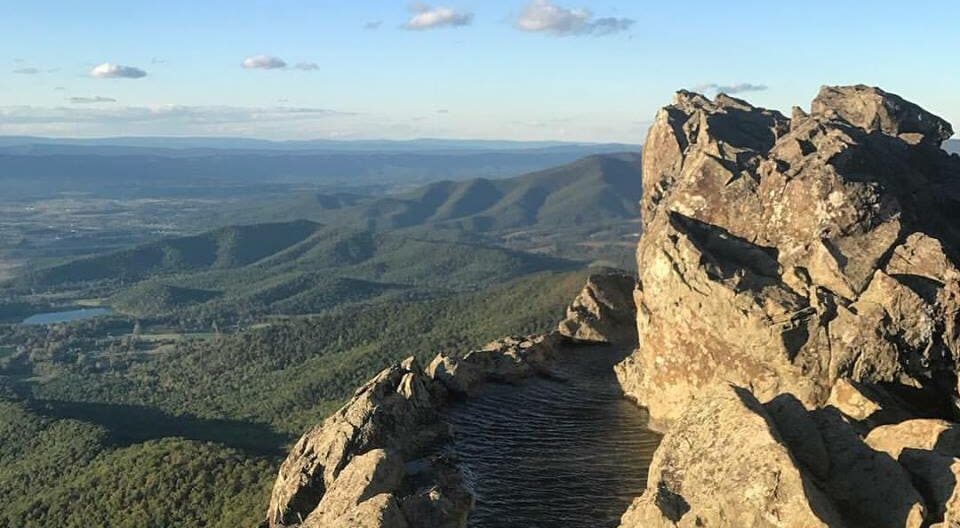 A hiking path going up a mountain with expansive views for miles of mountains and a lake